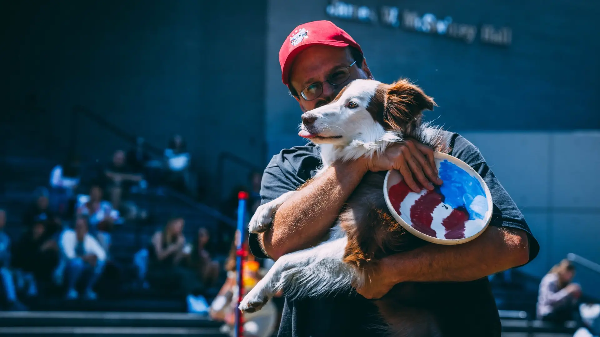 Performance handler holding lovingly his border collie Australian shepherd mix at a festival with a Hero bottom swirl performance frisbee disc