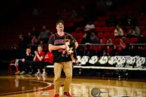 Performance Dogs of Ohio wowing the crowd at a basketball halftime show, with a frisbee dog flying high through the air to catch a disc mid-court as fans cheer in the background.